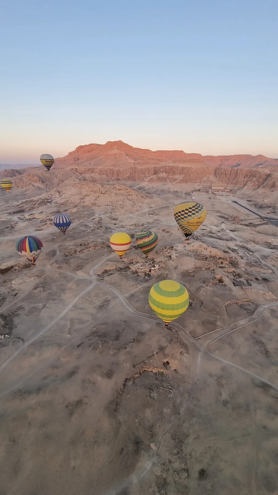 Hot air balloons above ancient sites and the cliffs of Luxor at dawn